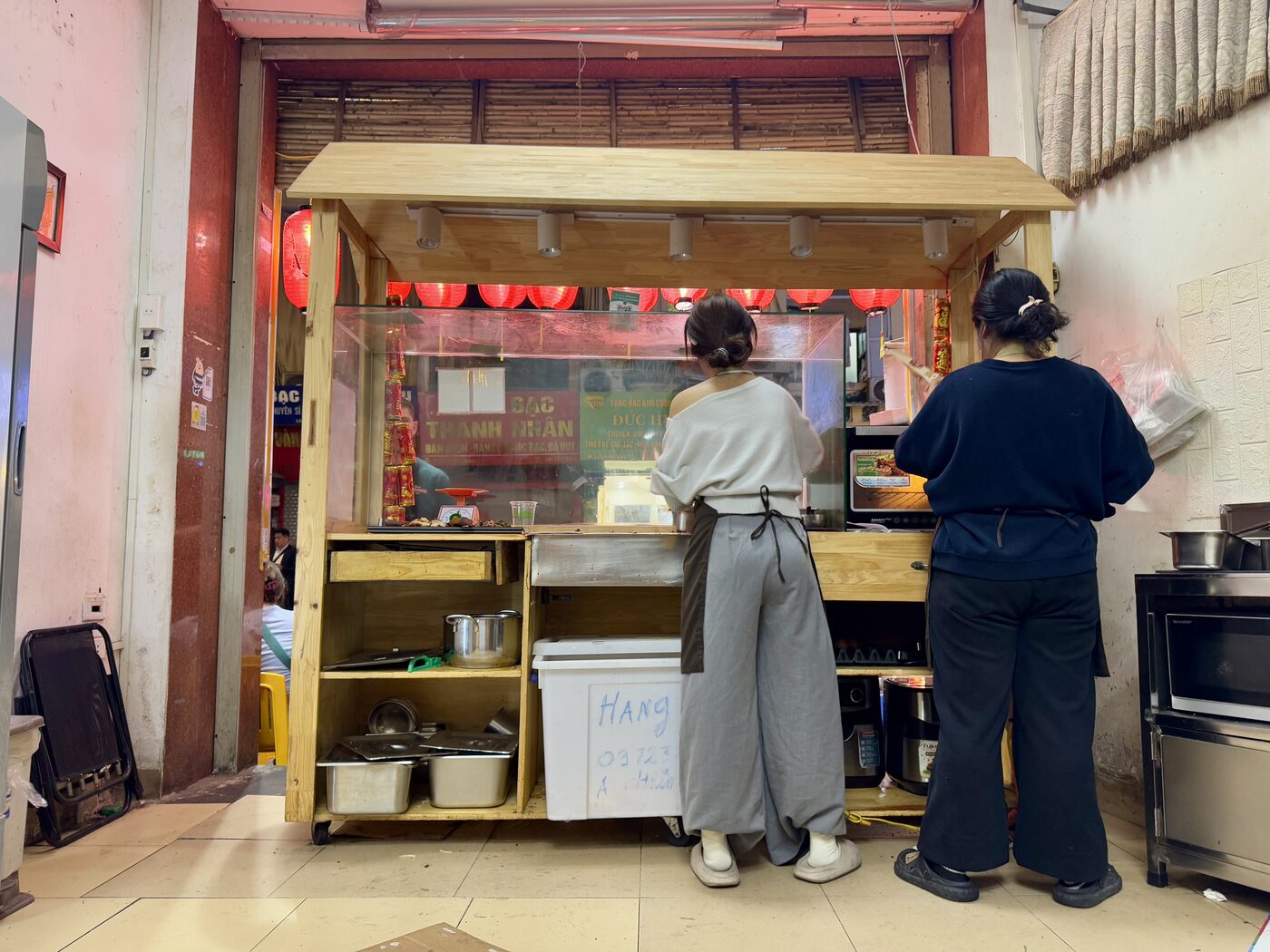 Two women working behind the counter of a small Hanoi kitchen