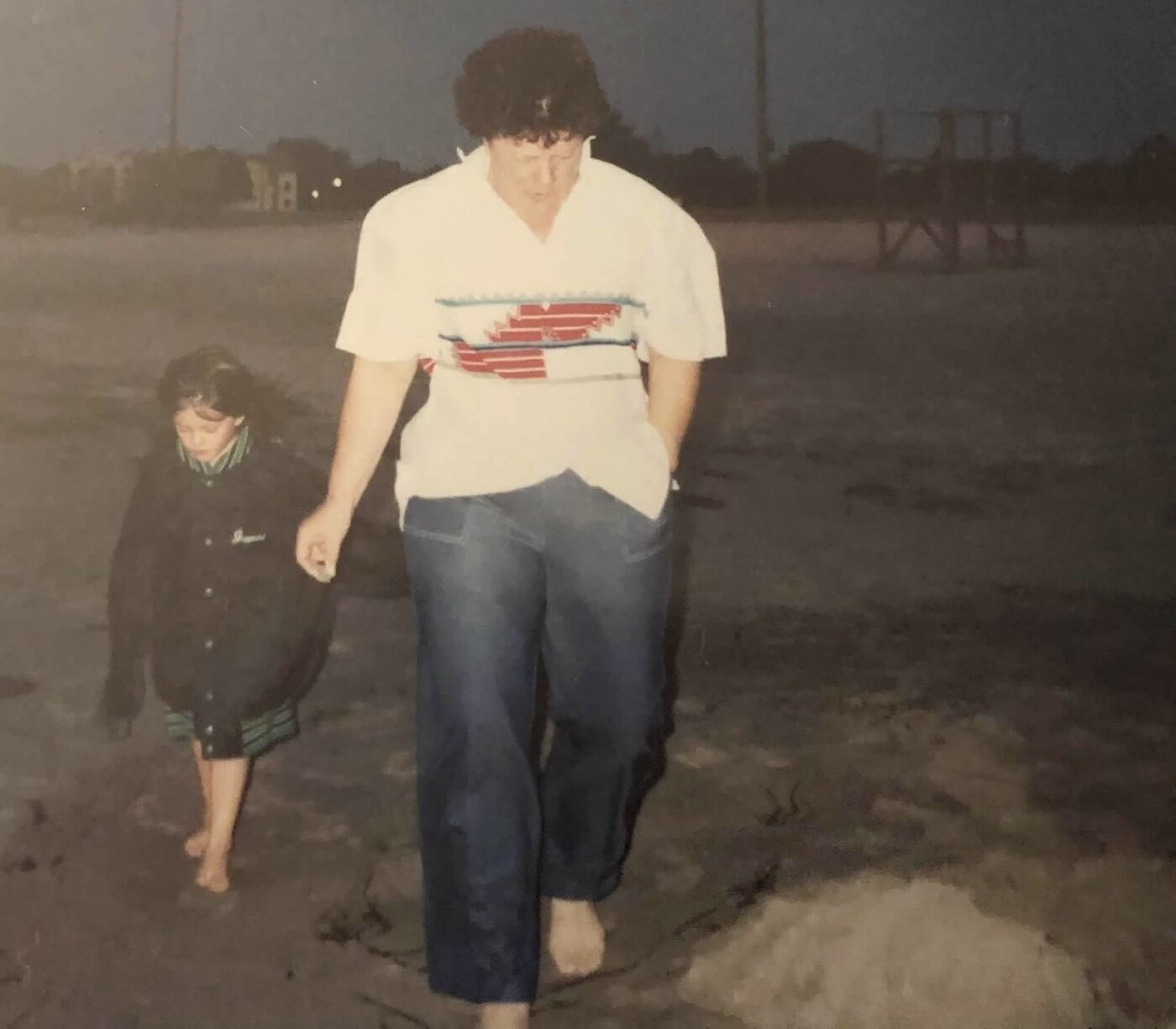 A young Karlee walking on the beach behind her grandmother