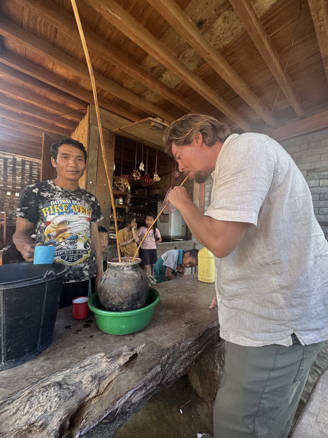 Jesse helping cook over a pot in a village kitchen in Laos