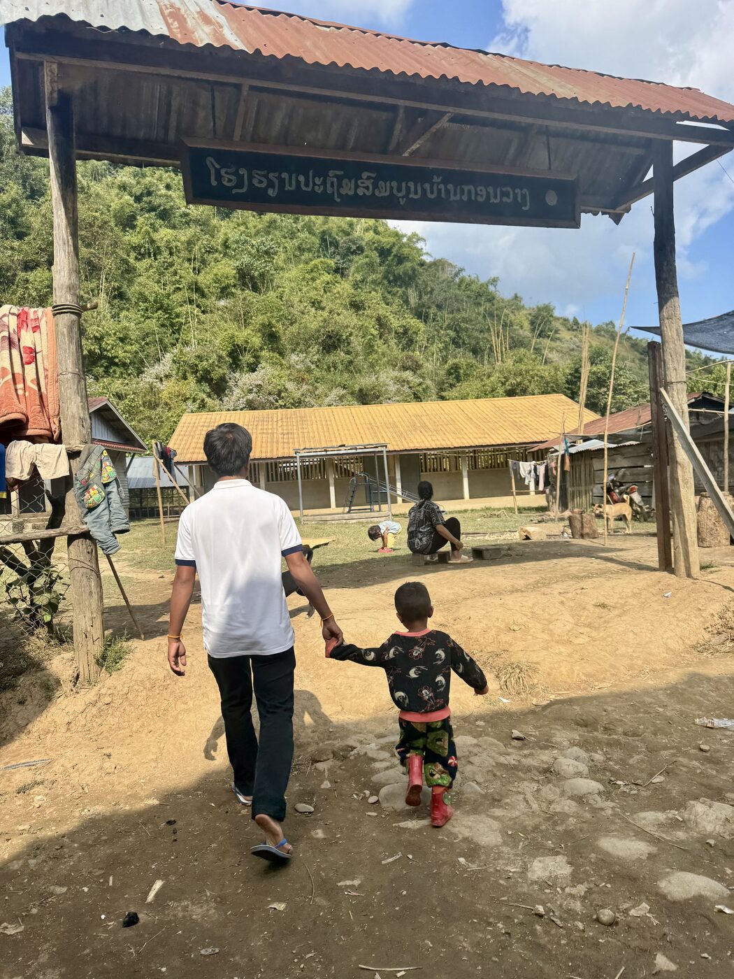 Jesse walking hand in hand with a young boy through a Lao village