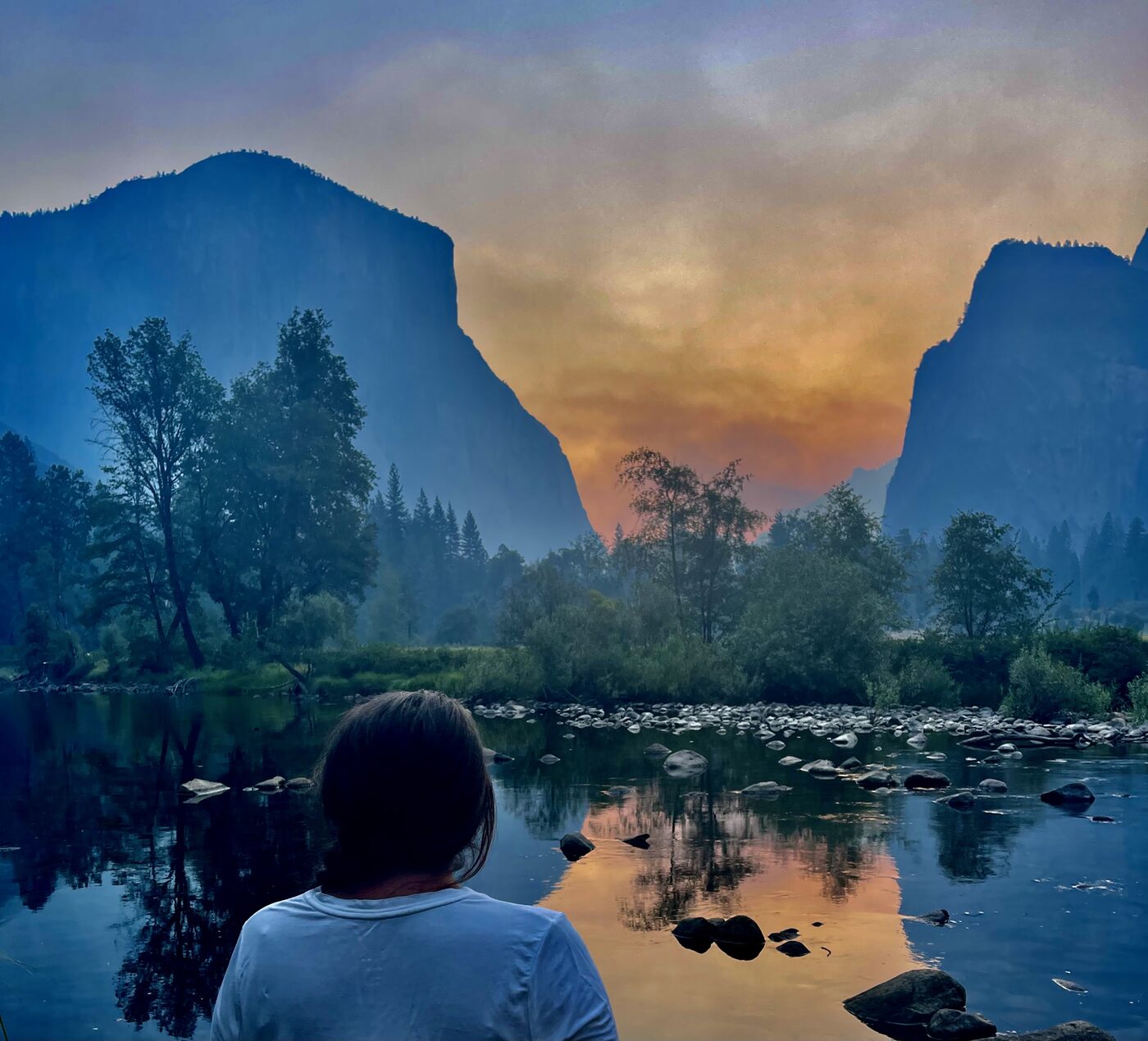 A figure looking out over a valley at first light, mist low over the river