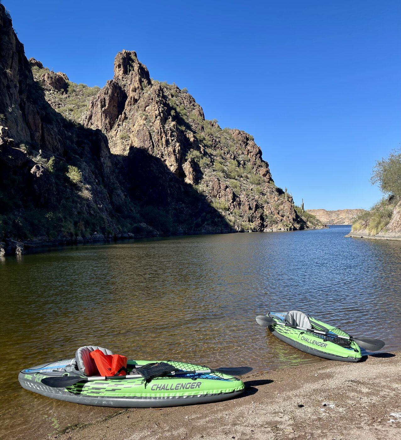 Two inflatable kayaks pulled up on a canyon lake shore