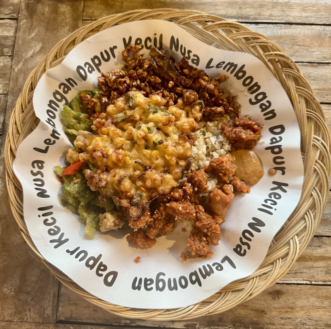 A warung plate piled with rice, tempeh, greens, and fried chicken