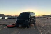 The van parked on the sand at Lake Powell as the sun goes down