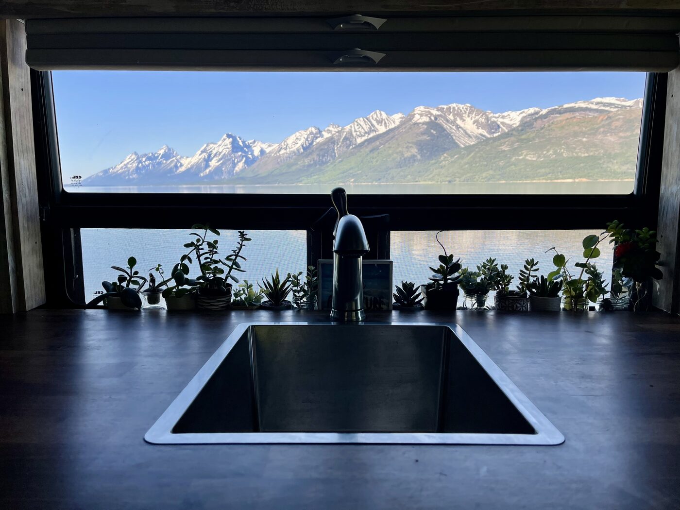 The galley sink under a window looking out at the Tetons across the lake