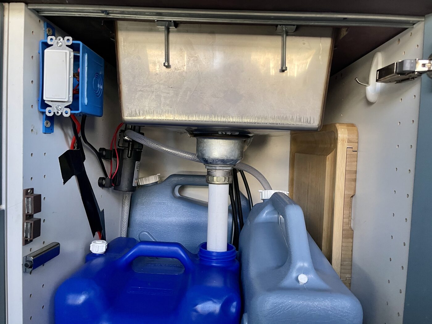 The van's water tanks and electrical bay behind an open cabinet
